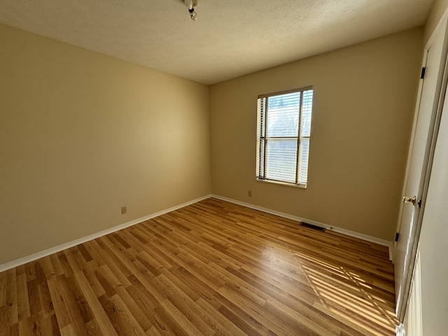 unfurnished room featuring light hardwood / wood-style flooring and a textured ceiling