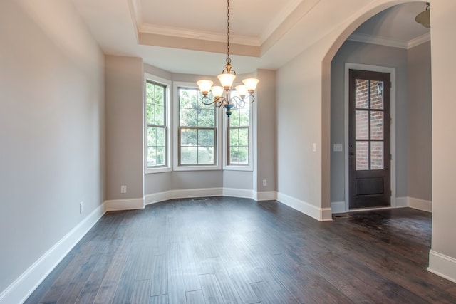 empty room with a chandelier, dark hardwood / wood-style floors, a raised ceiling, and ornamental molding