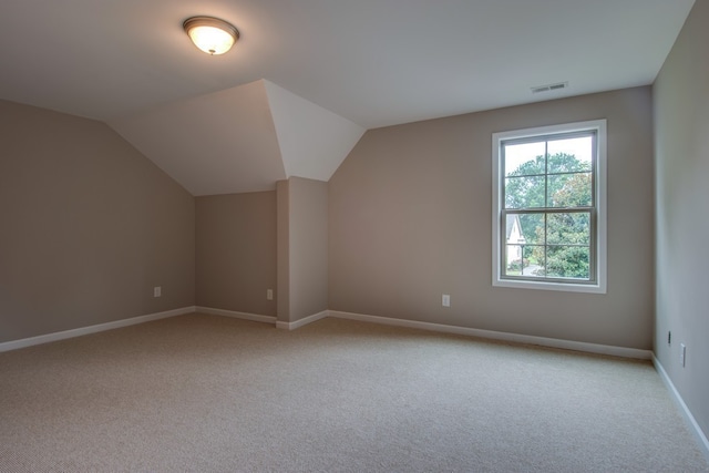 additional living space featuring light colored carpet and lofted ceiling