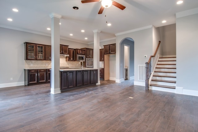 kitchen featuring appliances with stainless steel finishes, dark brown cabinetry, crown molding, dark wood-type flooring, and sink