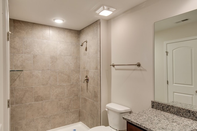 bathroom with vanity, toilet, and a tile shower