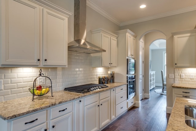 kitchen featuring decorative backsplash, appliances with stainless steel finishes, wall chimney range hood, white cabinets, and dark hardwood / wood-style floors