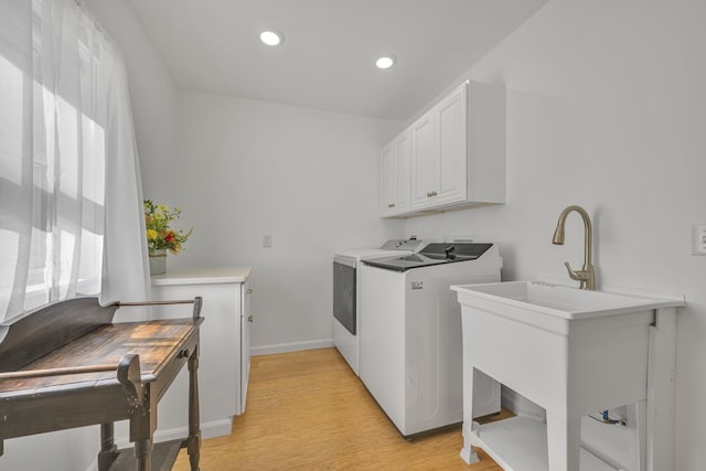 laundry area with cabinets, light hardwood / wood-style floors, and independent washer and dryer