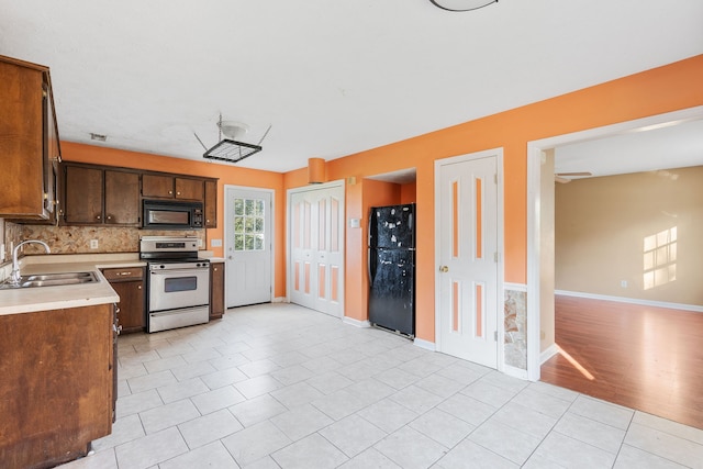 kitchen with sink, tasteful backsplash, light hardwood / wood-style flooring, and black appliances