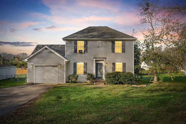 colonial home with a yard and a garage