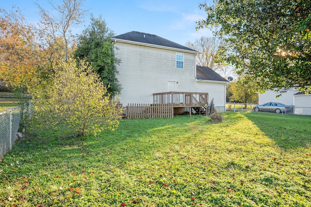 rear view of property featuring a lawn and a deck