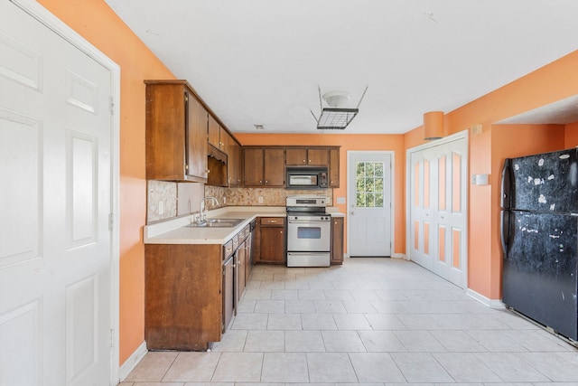 kitchen with black appliances, decorative backsplash, light tile patterned floors, and sink