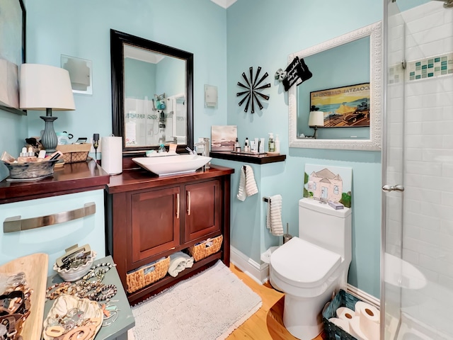 bathroom featuring vanity, toilet, a shower with shower door, and wood-type flooring