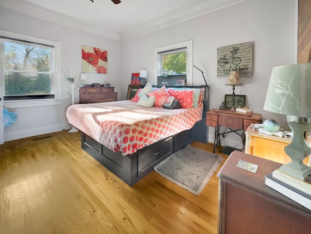 bedroom with ceiling fan, ornamental molding, and light hardwood / wood-style flooring