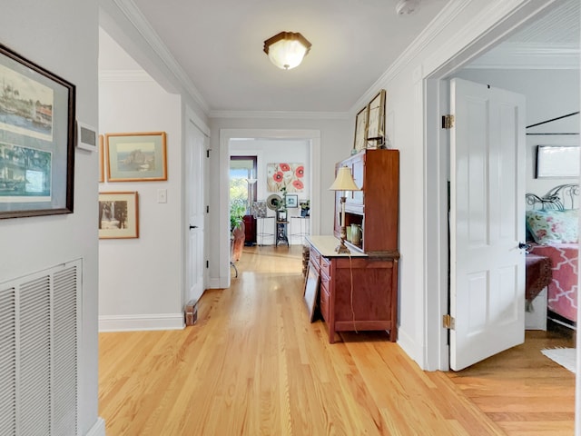 corridor with ornamental molding and light hardwood / wood-style flooring