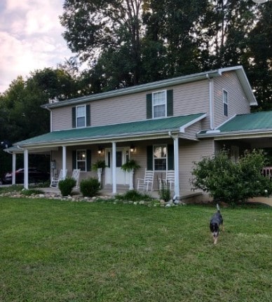 view of front facade with covered porch, a carport, and a front yard