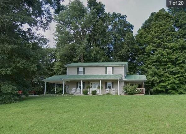 country-style home with covered porch, an attached carport, and a front yard