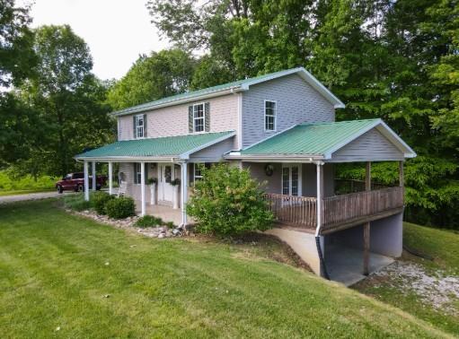 1159 New Hope Rd, Celina, TN 38551 - farmhouse-style home with a front lawn, covered porch, and view of scattered trees
