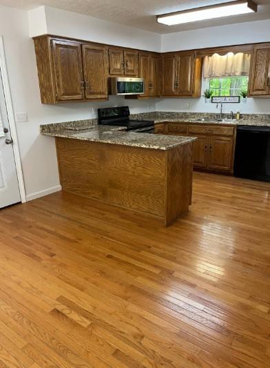 1159 New Hope Rd, Celina, TN 38551 - kitchen featuring black appliances, a sink, light wood-type flooring, dark stone counters, and a peninsula