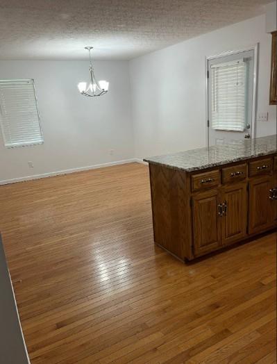 1159 New Hope Rd, Celina, TN 38551 - kitchen with light wood-type flooring, a chandelier, pendant lighting, a peninsula, and baseboards
