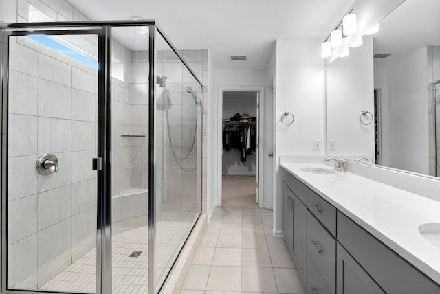 bathroom with a shower with shower door, vanity, and tile patterned flooring