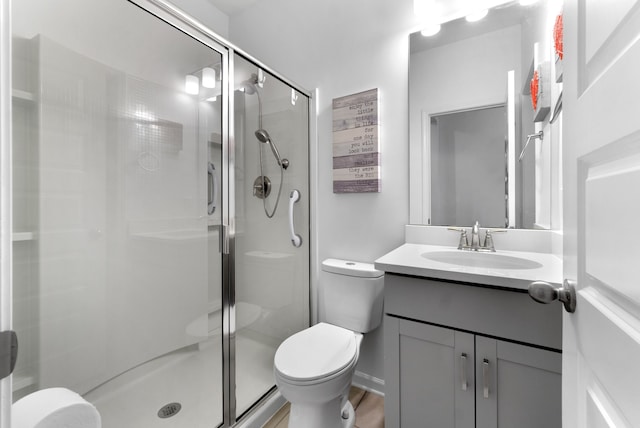 bathroom featuring toilet, vanity, and a shower with door