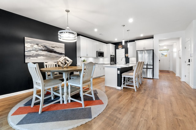 dining space with sink and light wood-type flooring