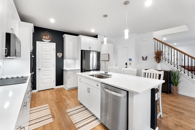 kitchen featuring a breakfast bar, sink, white cabinetry, a kitchen island with sink, and stainless steel appliances