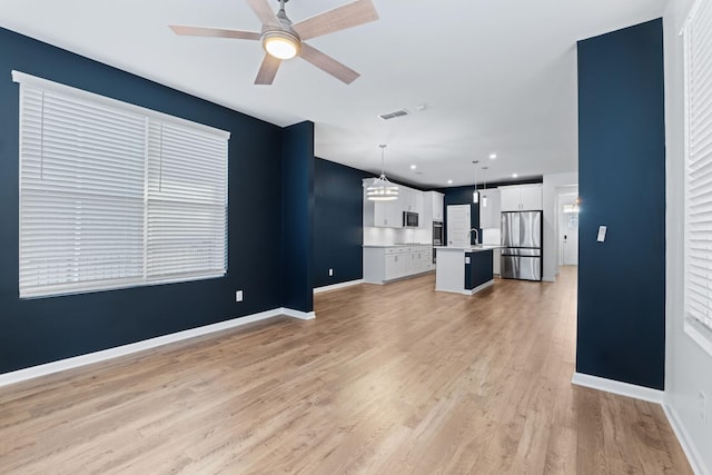 unfurnished living room featuring ceiling fan and light hardwood / wood-style floors