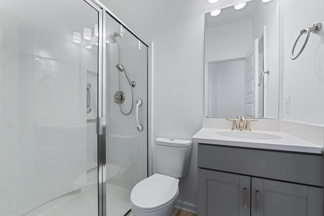 bathroom featuring toilet, vanity, and a shower with door