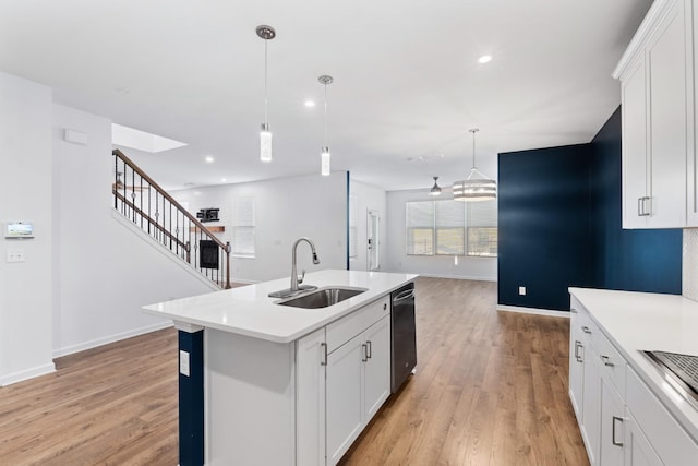 kitchen featuring hanging light fixtures, sink, an island with sink, and white cabinetry