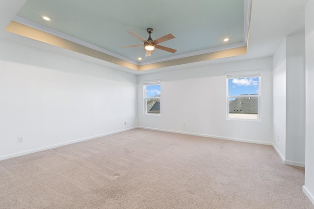 spare room featuring ceiling fan, ornamental molding, light colored carpet, and a tray ceiling