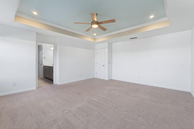 spare room with light carpet, crown molding, and a tray ceiling