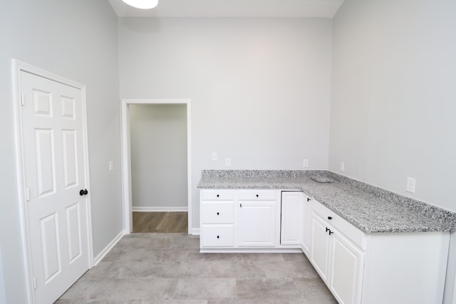 kitchen featuring light stone counters and white cabinets