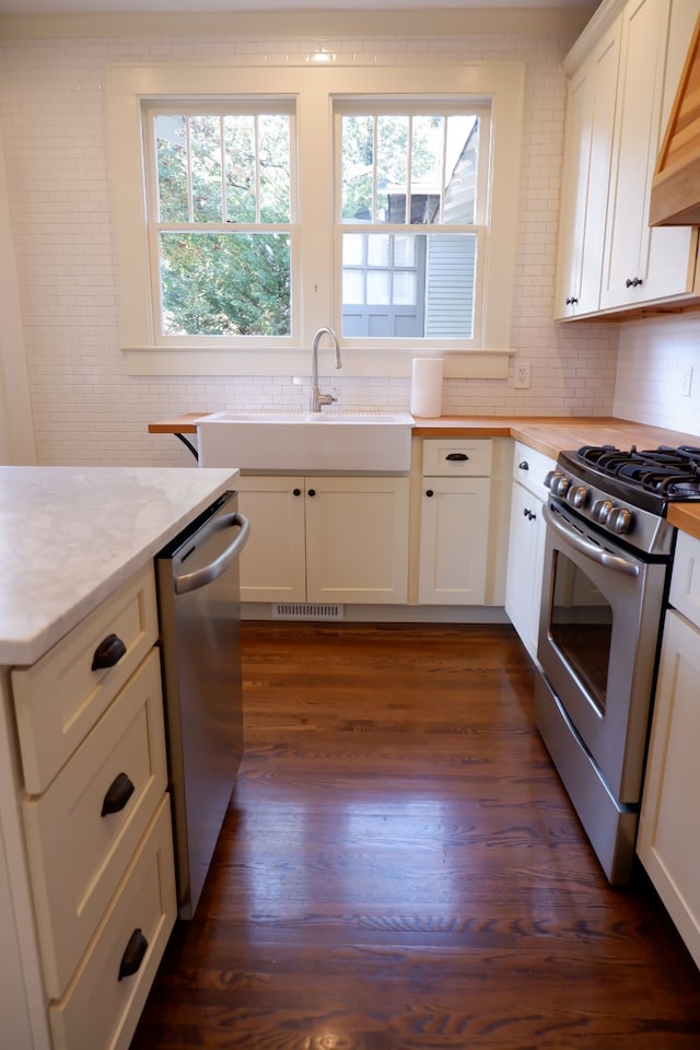 kitchen featuring sink, dark hardwood / wood-style flooring, light stone counters, white cabinetry, and stainless steel appliances