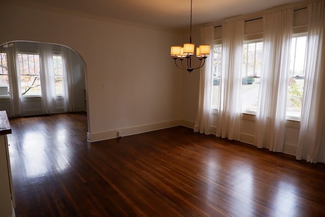 unfurnished dining area featuring a wealth of natural light, dark hardwood / wood-style floors, and a notable chandelier