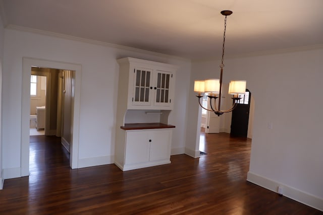 unfurnished dining area with dark hardwood / wood-style flooring, crown molding, and a chandelier