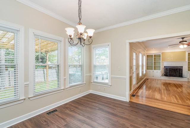 unfurnished dining area featuring ceiling fan with notable chandelier, ornamental molding, dark wood-type flooring, and built in shelves