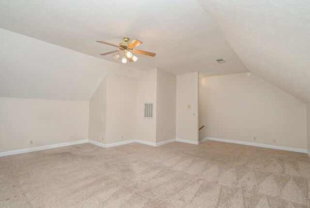 additional living space featuring ceiling fan, light colored carpet, a textured ceiling, and vaulted ceiling