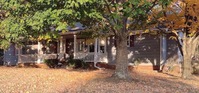 view of property hidden behind natural elements with covered porch