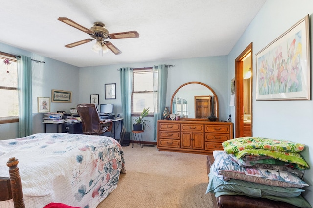 bedroom with light carpet, ensuite bathroom, multiple windows, and ceiling fan