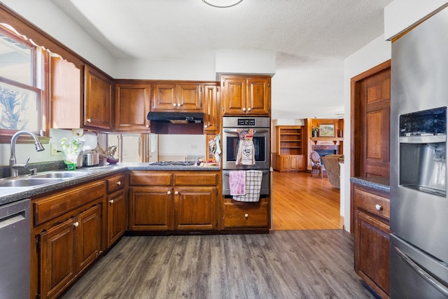 kitchen featuring a textured ceiling, sink, stainless steel appliances, and dark hardwood / wood-style floors