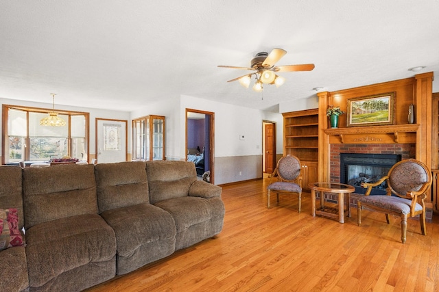 living room featuring a brick fireplace, ceiling fan, and light hardwood / wood-style flooring