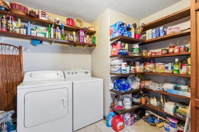 laundry room with washer and clothes dryer, light tile patterned floors, and a textured ceiling