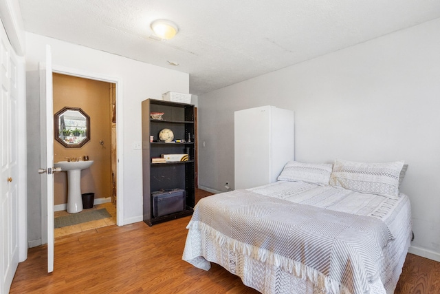 bedroom with sink, hardwood / wood-style flooring, and ensuite bathroom