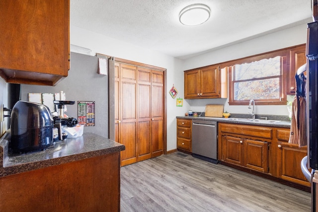 kitchen featuring dishwasher, a textured ceiling, light hardwood / wood-style floors, and sink