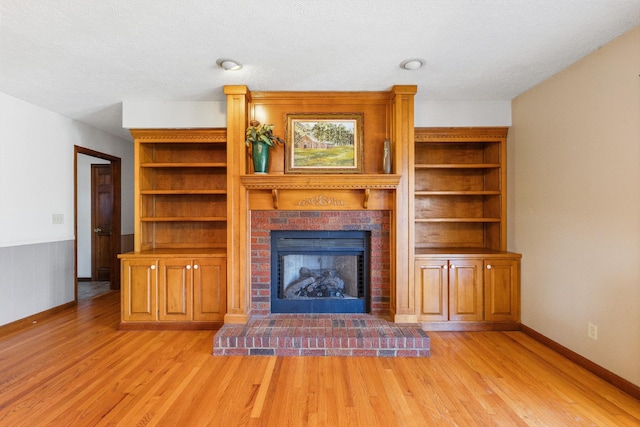 unfurnished living room featuring a textured ceiling, light hardwood / wood-style floors, and a fireplace