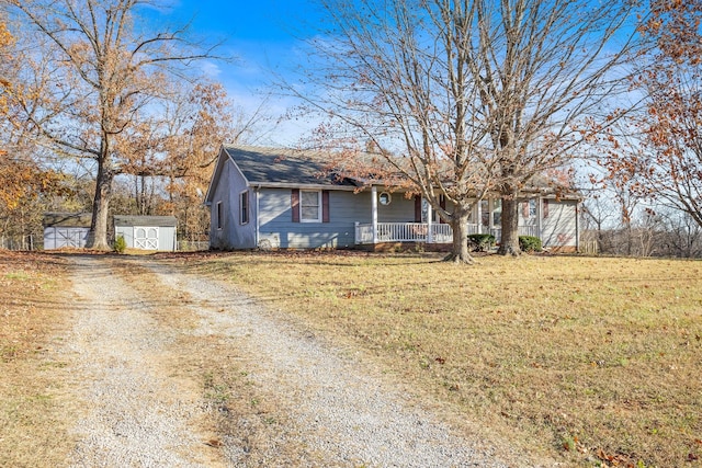 view of front of house featuring a front lawn, covered porch, and a shed