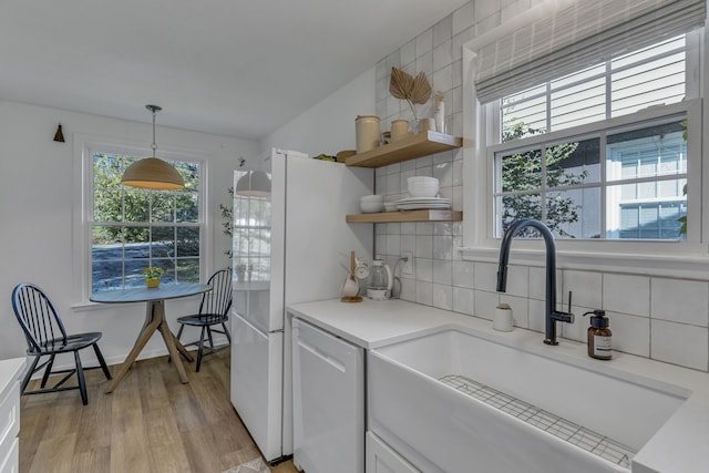 kitchen featuring tasteful backsplash, sink, decorative light fixtures, light hardwood / wood-style flooring, and dishwasher