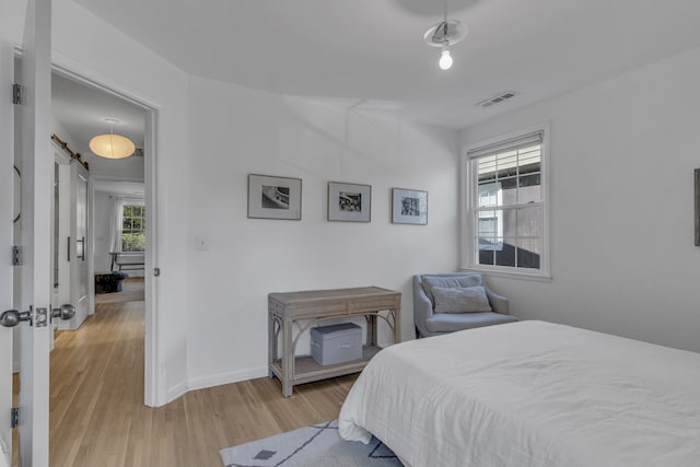 bedroom featuring light hardwood / wood-style floors and a barn door