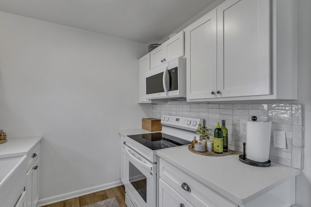 kitchen featuring decorative backsplash, white cabinetry, white appliances, and dark wood-type flooring