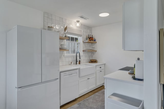 kitchen with decorative backsplash, light wood-type flooring, white appliances, sink, and white cabinets