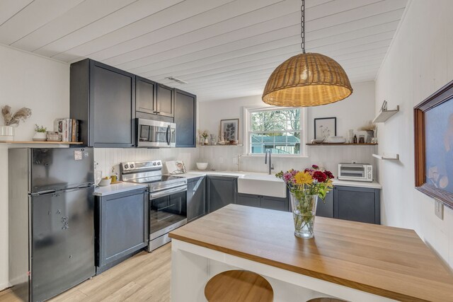 kitchen featuring decorative light fixtures, light hardwood / wood-style floors, sink, and appliances with stainless steel finishes