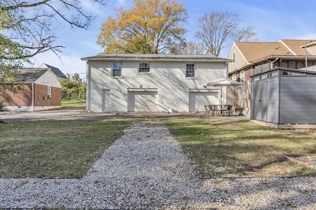 back of house featuring a patio area, a yard, and a garage