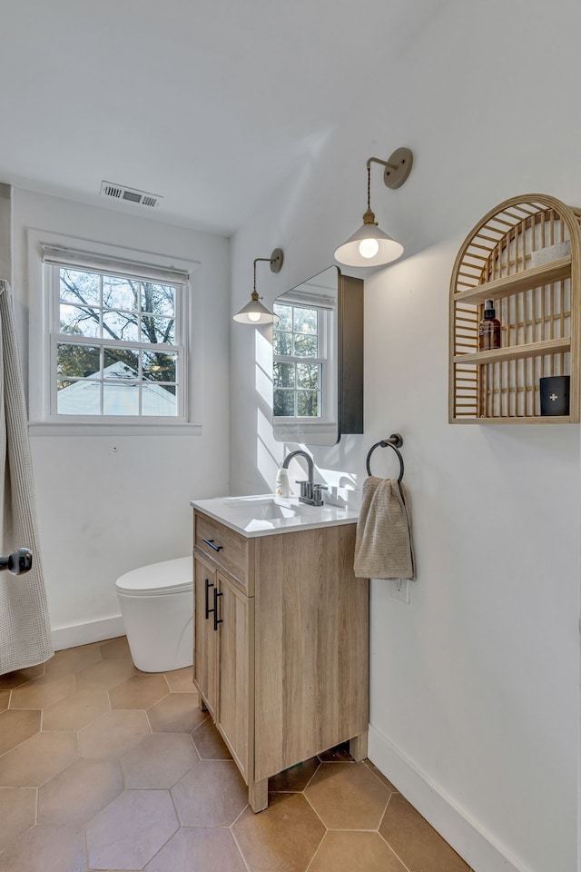 bathroom featuring tile patterned floors, vanity, a healthy amount of sunlight, and toilet